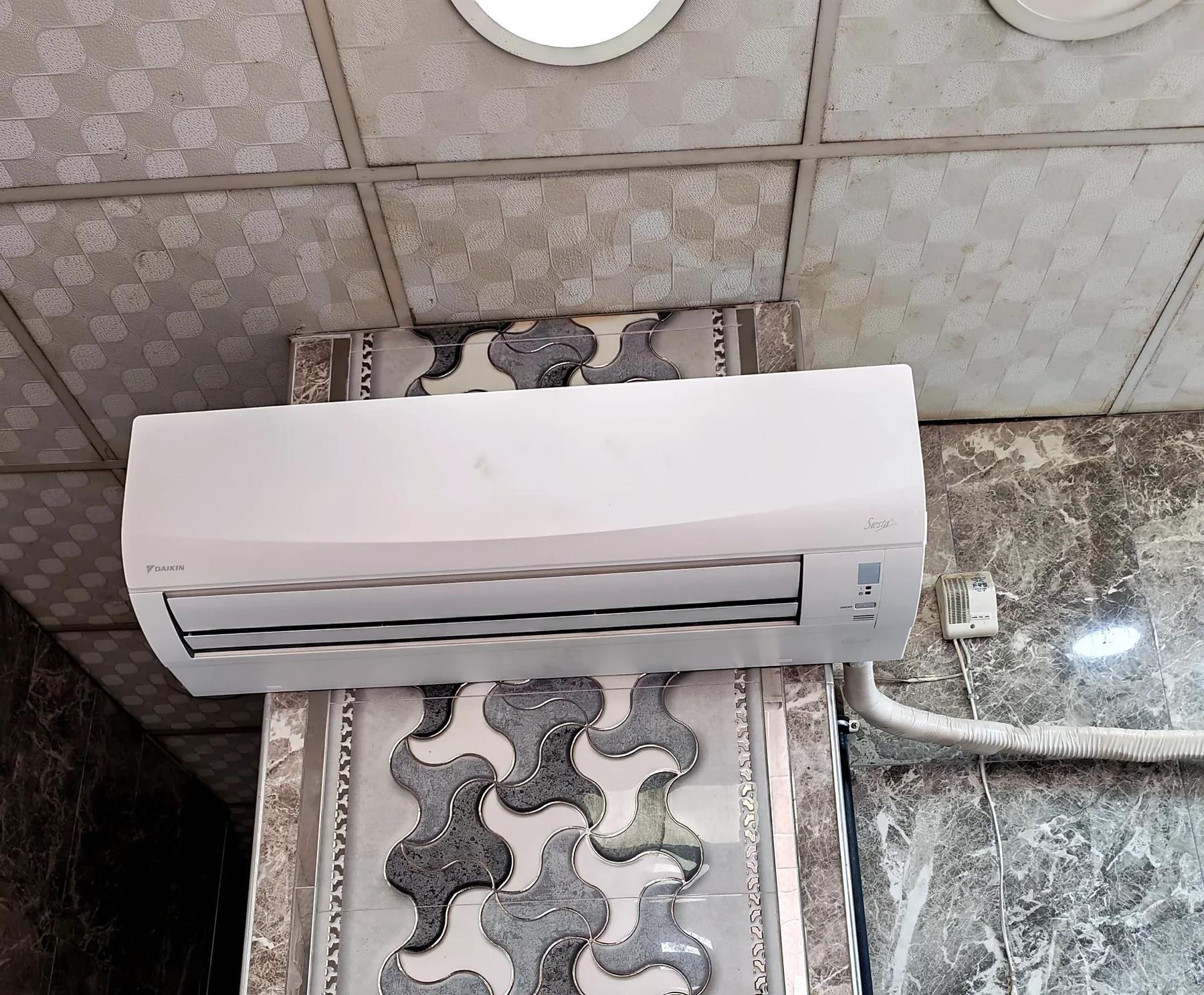 Desenli fayans duvara monte edilmiş Daikin Siesta iç ünite