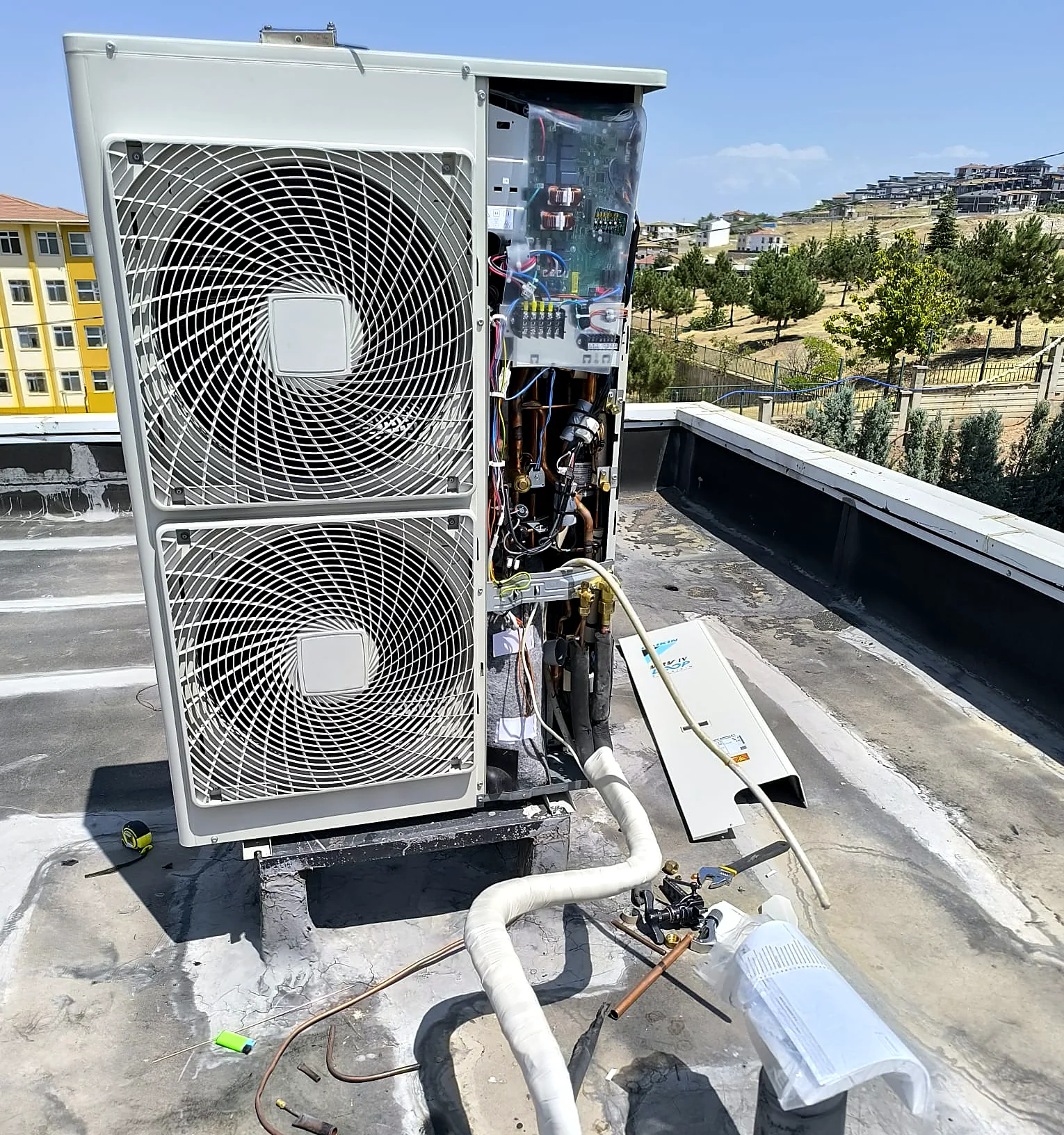 Çatıya kurulmuş, kapağı açık Daikin VRV IV dış ünite ve boru bağlantıları